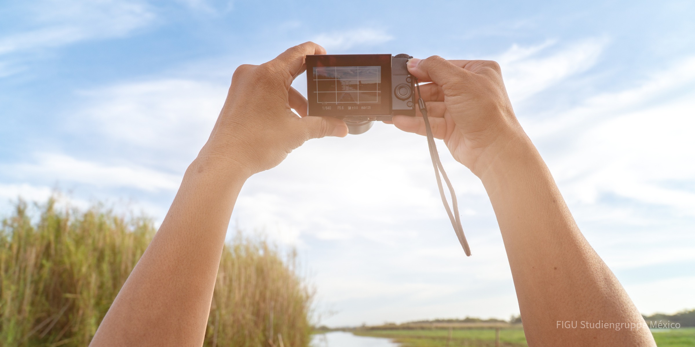 Manos sosteniendo una cámara para tomar una fotografía al aire libre.