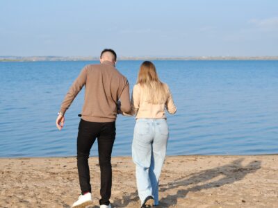 Pareja de espaldas caminando de la mano por una playa.